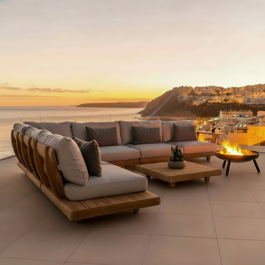 Outdoor patio set with sectional sofa, coffee table, and fire pit against a sunset backdrop.