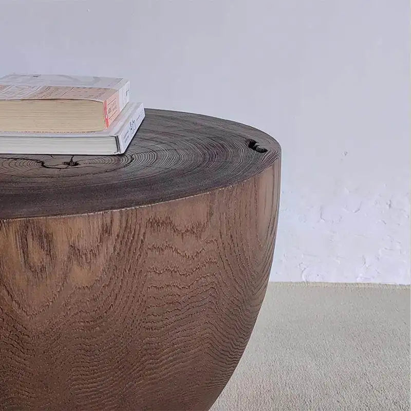 Wooden side table with a textured surface and books on top against a plain wall.
