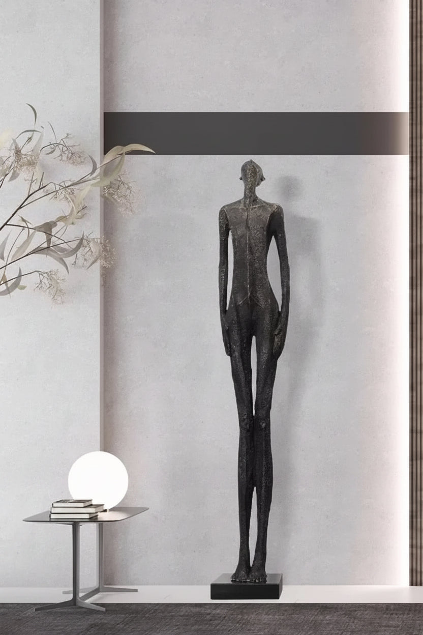 Statue of a person in a modern interior setting with a neutral color scheme.