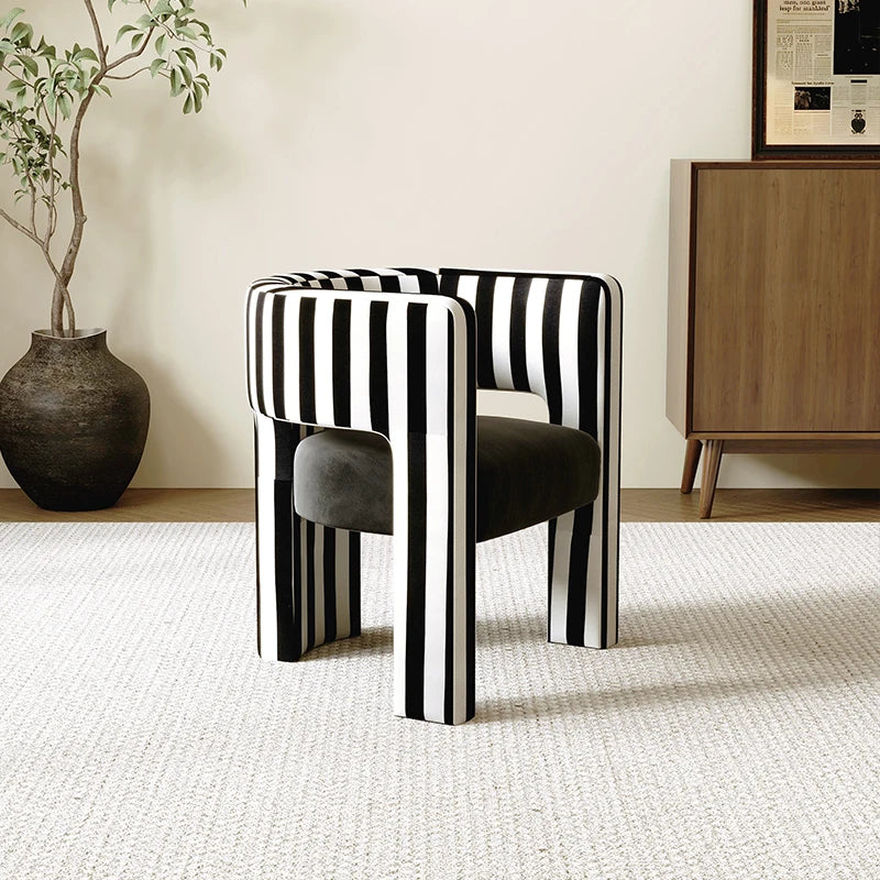 Black and white striped chairs in a room with a plant and wooden cabinet.