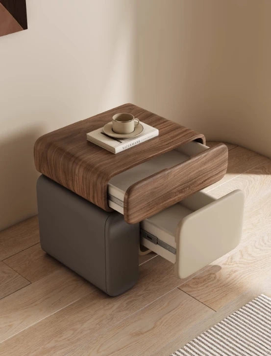 Wooden side table with a drawer and a cup on top, in a minimalistic room.