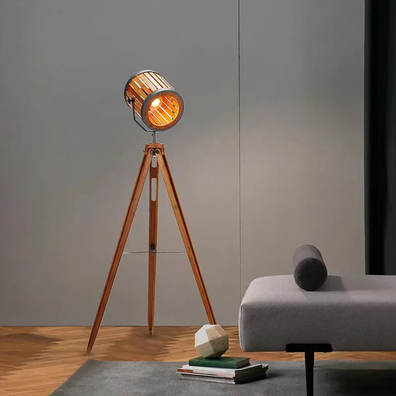 Wooden tripod floor lamp in a room with a gray wall and a small table.