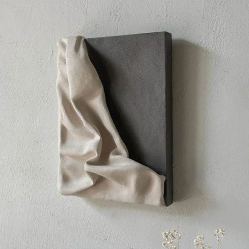Beige fabric draped over a dark rectangular block on a light gray background