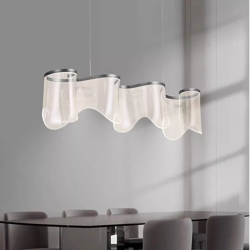 Modern pendant light fixture hanging above a dining table with chairs in a minimalistic setting.