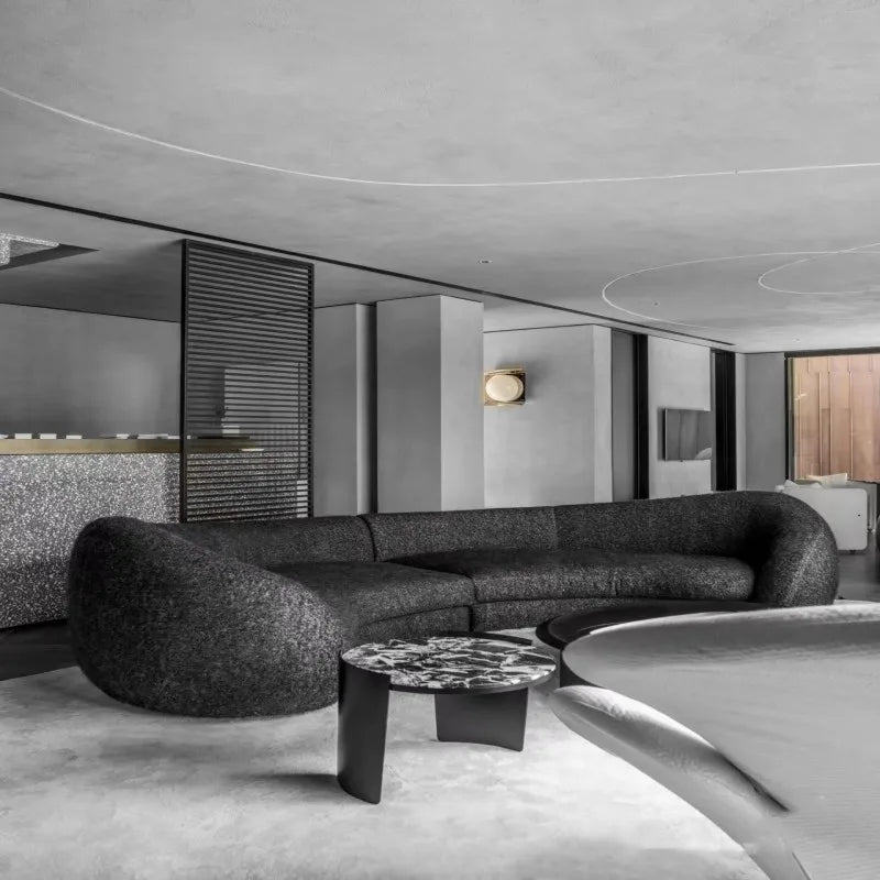 Modern living room with a curved black sofa and round coffee table.