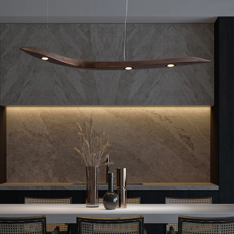 Modern pendant light hanging above a dining table with a stone wall background