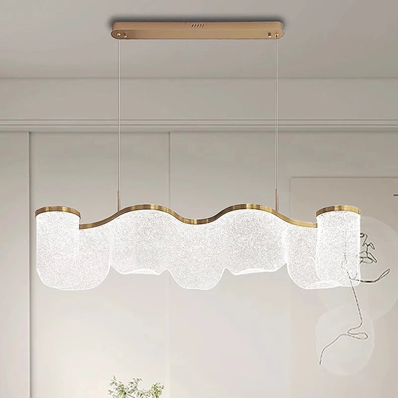 Modern pendant light fixture with wavy design and gold accents on a neutral background