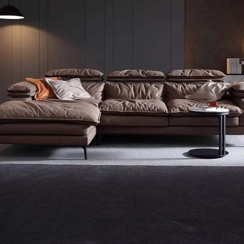 Large brown sectional sofa with cushions in a dimly lit room.