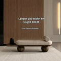 Modern bench with wooden legs and beige cushion in a minimalistic room.
