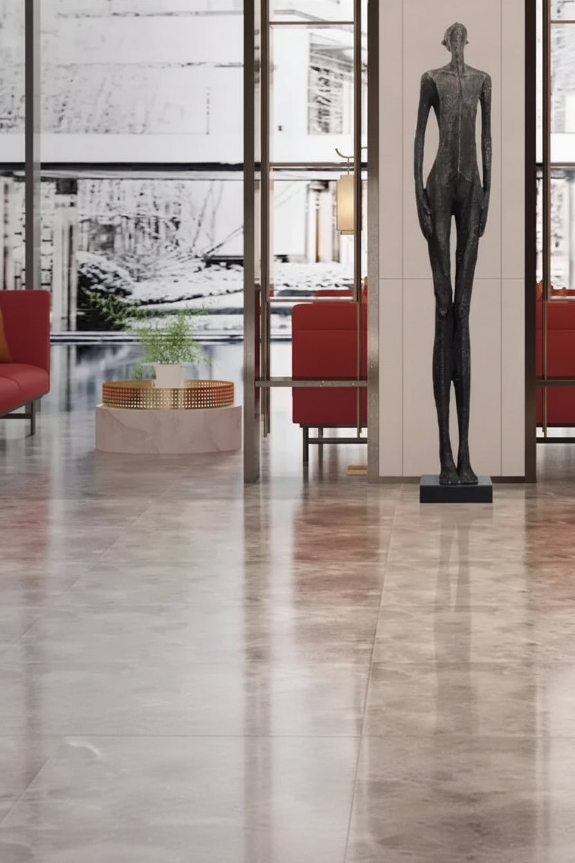 Statue in a modern interior setting with red chairs and large windows.